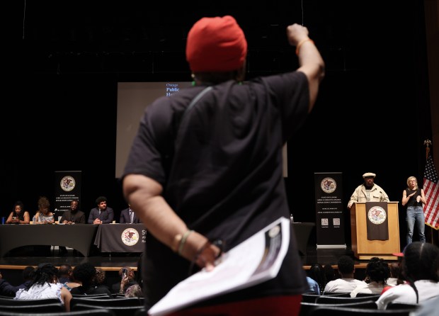 An audience member stands with a raised fist as Fred Hampton Jr., at podium, speaks during the African Descent-Citizens Reparations Commission (ADCRC) public hearing at Kennedy-King College on July 13, 2024, in Chicago. (John J. Kim/Chicago Tribune)