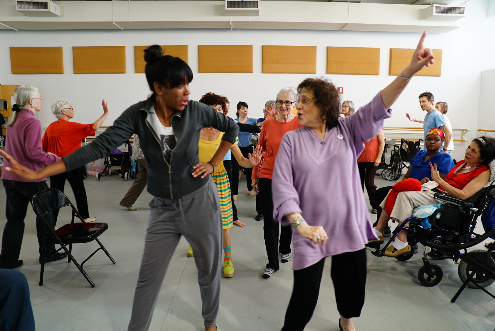 A photograph showing older adults exercising in a room.