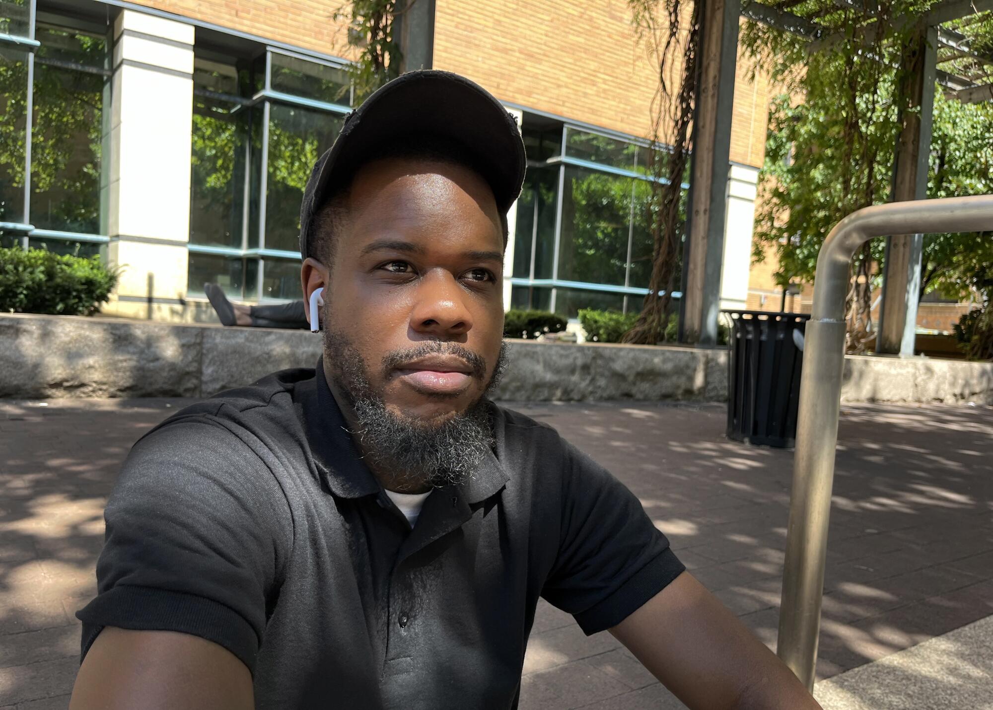 Brian Clark seated on a shaded sidewalk in Philadelphia