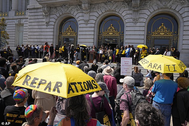 People listen during a rally in support of reparations for African Americans outside City Hall in San Francisco, Tuesday, Sept. 19, 2023