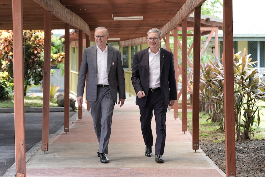 two met in suits walk in a sheltered outside area