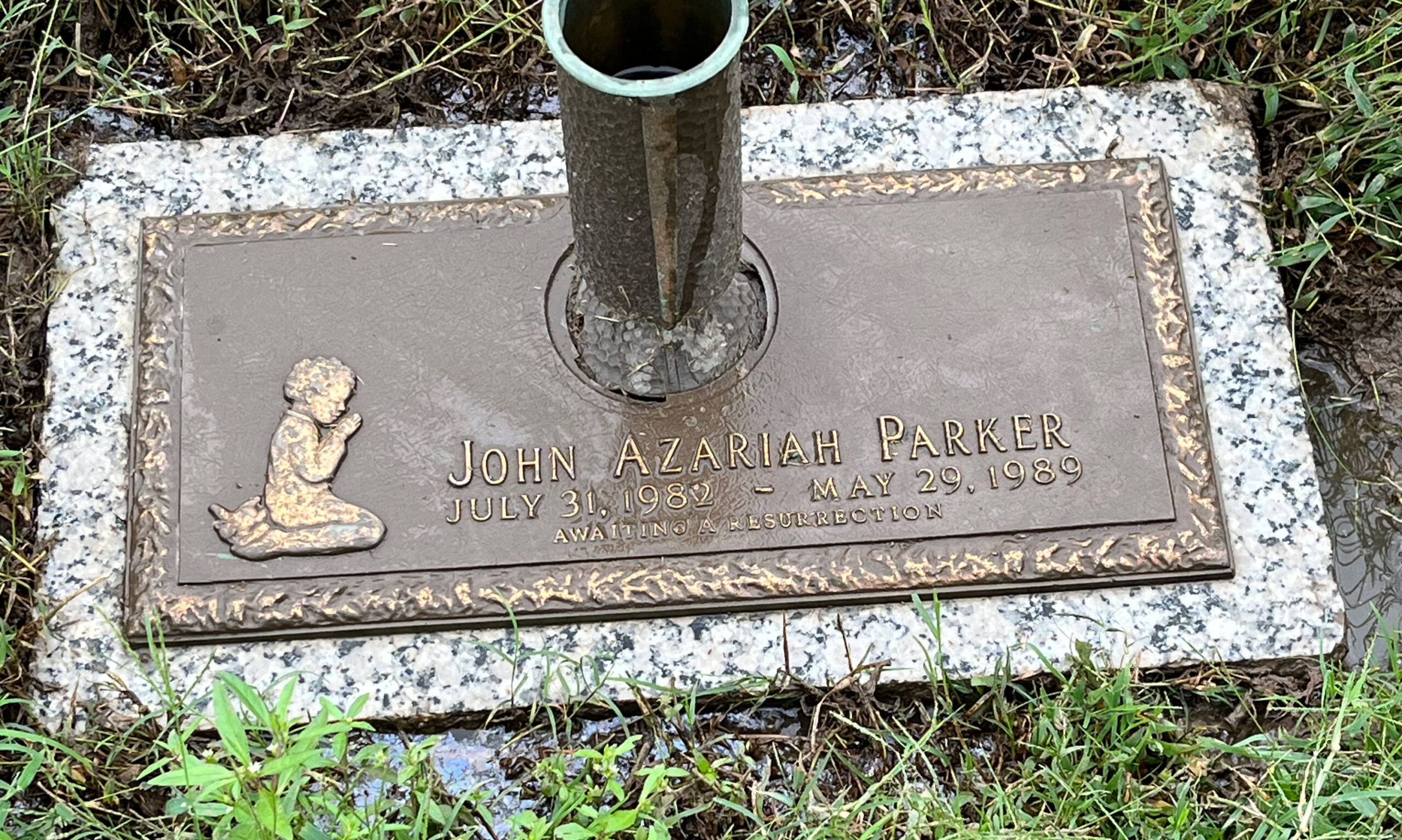 A photo of a gravestone in a cemetery with the name John Azariah Parker engraved on it.