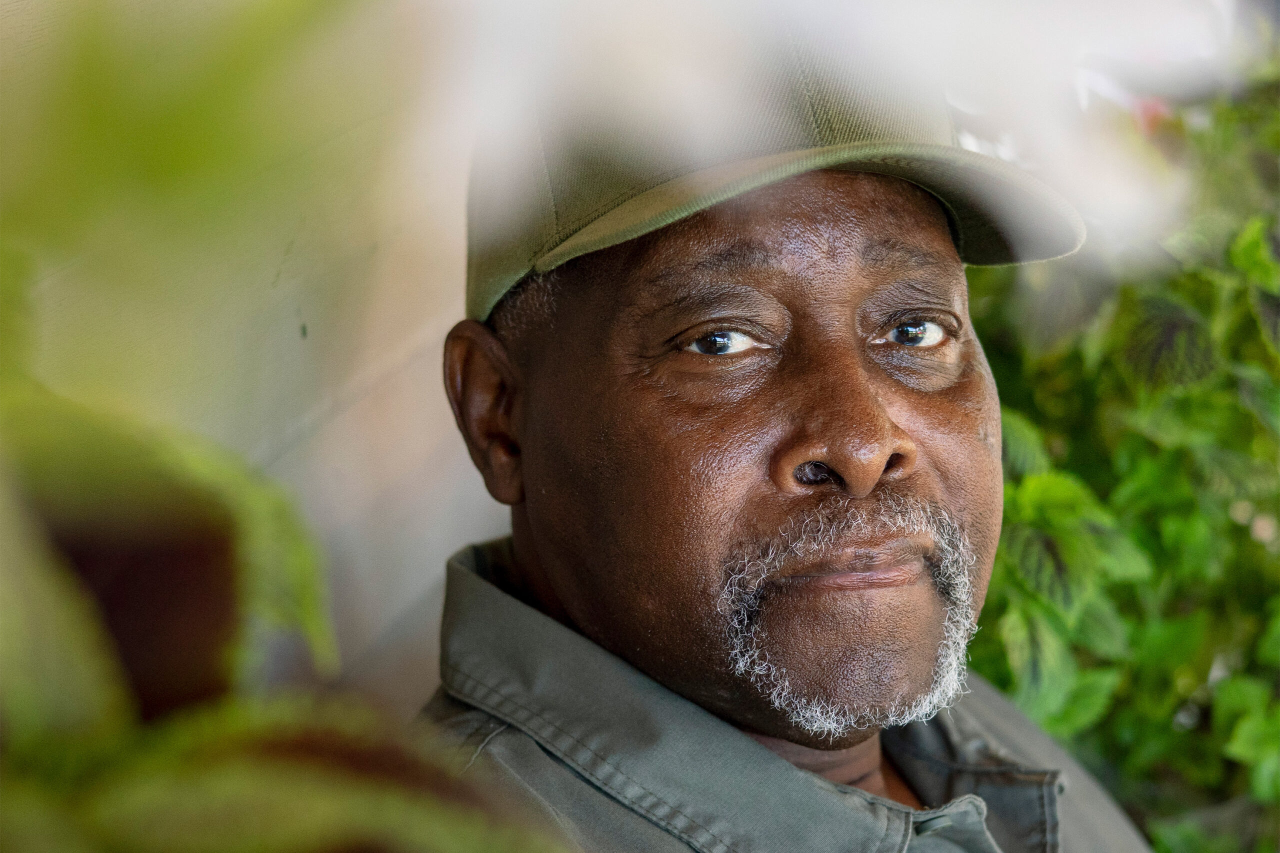 A photo of Joshua McCray, with blurred plants in the foreground framing his face.