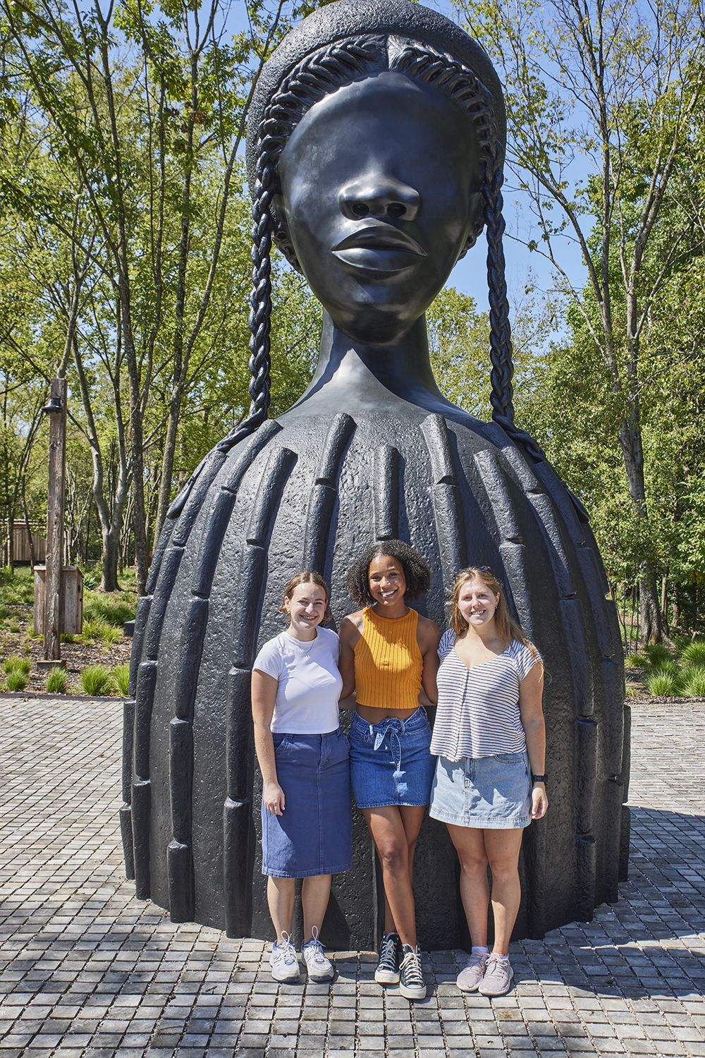 Stanford Law students, from left to right: Sarah Wishingrad, Joelle Miller, and Kate Hughes pose before the Brick House sculpture by Simone Leigh, which welcomes visitors at the entrance of Freedom Monument Sculpture Park.