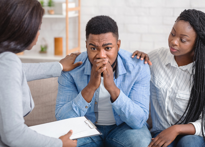 Caring black wife and counselor supporting man during psychotherapy session