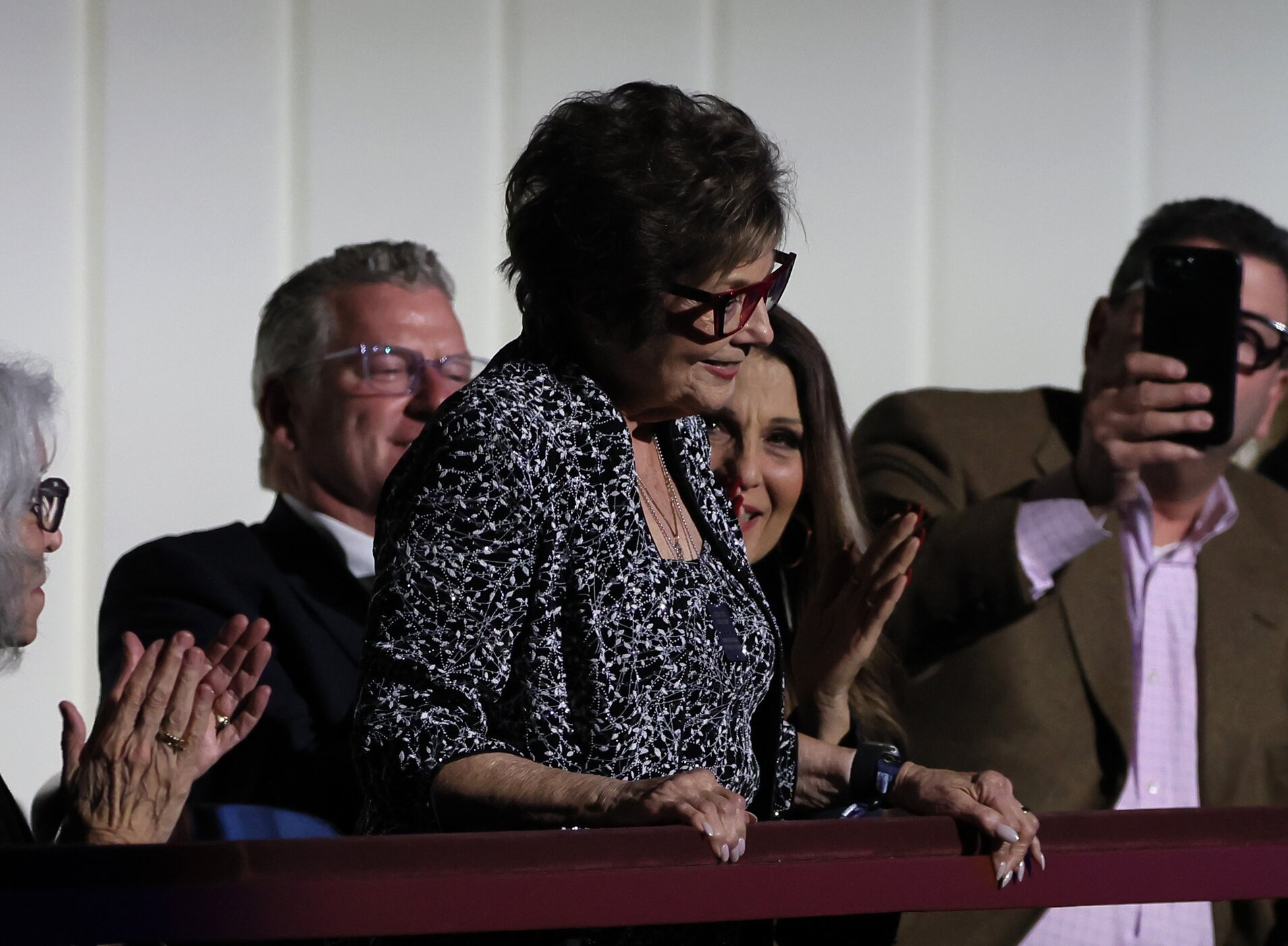 elderly woman with short brown hair receiving applause while accepting an award