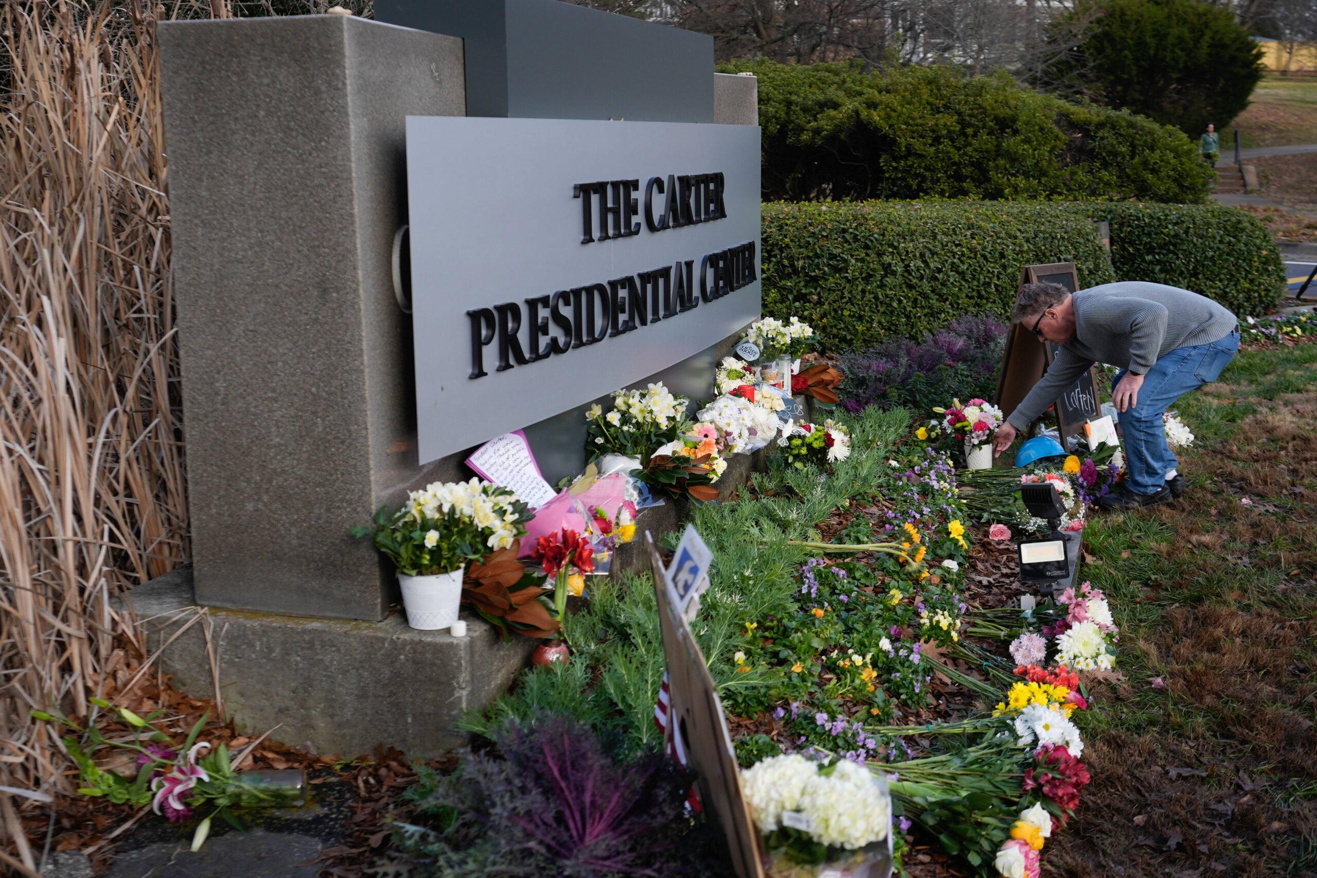 A man places flowers in tribute to former President Jimmy Carter at the entrance to the Jimmy...