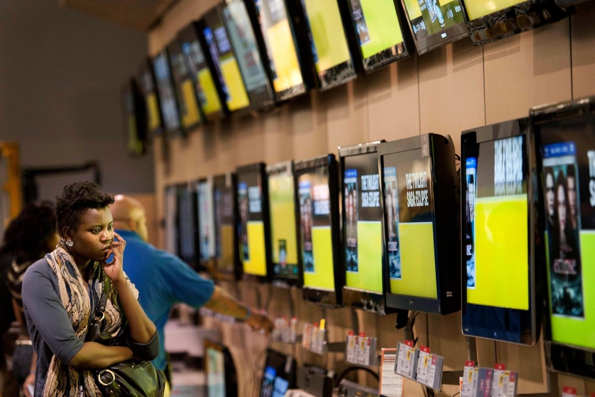 A woman ponders which television to buy at an electronics store in Atlanta in 2010.