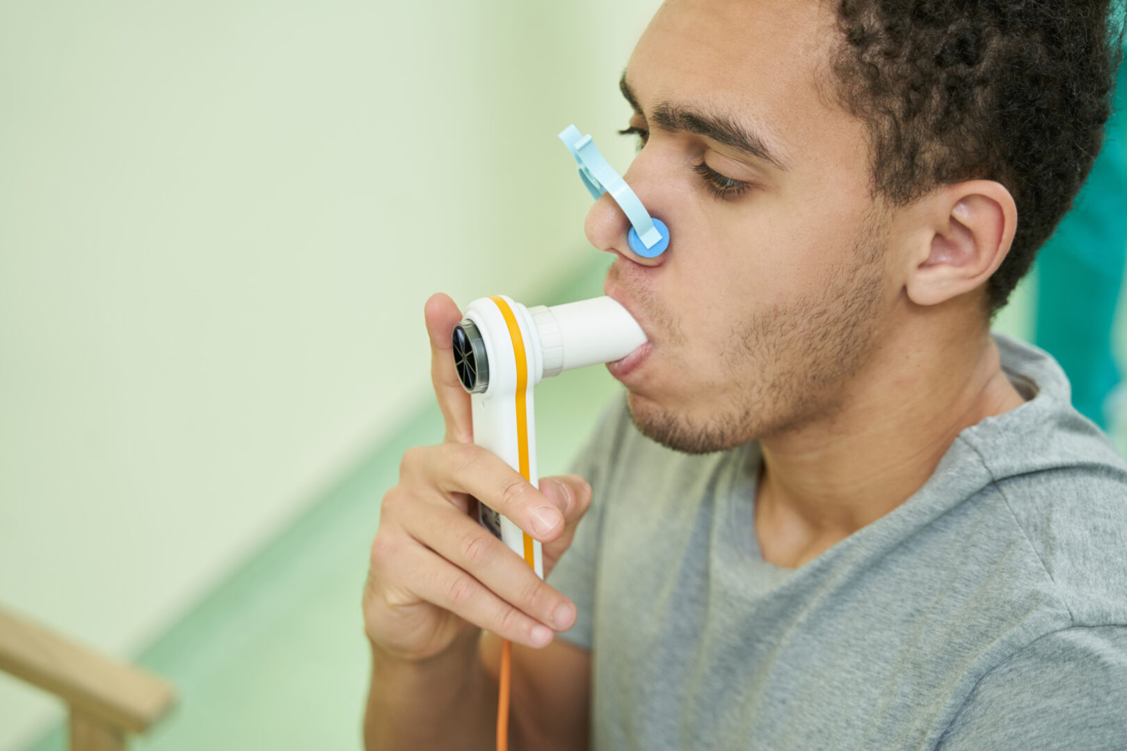 Man putting spirometer tube into mouth and breathing air inside it